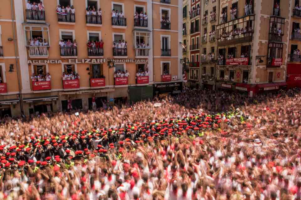  A band surrounded by police plays as revellers celebrate the 'Chupinazo', which sees a rocket let off to announce the start of the festival