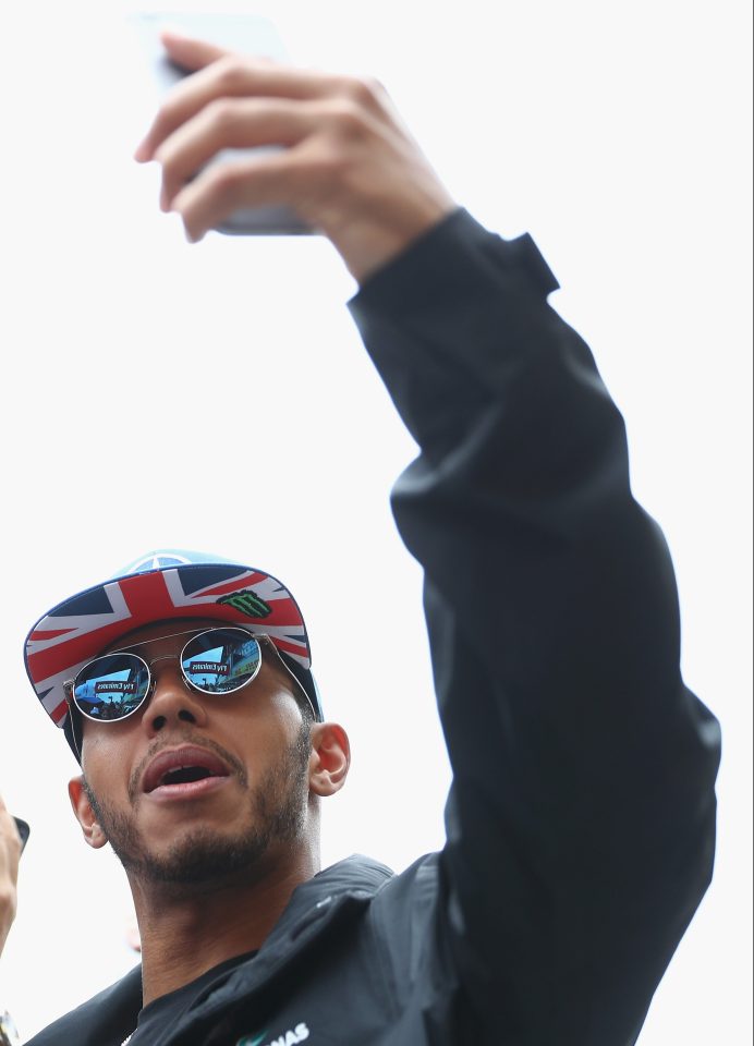 Lewis Hamilton takes the time to pose for selfies with fans in his Union Flag cap