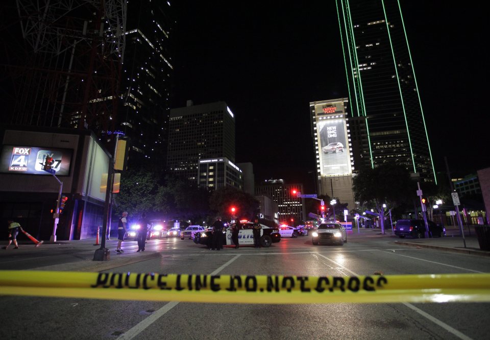 Dallas police officers face protesters on the corner of on the corner of Ross Avenue and Griffin Street after eleven police officers were shot 