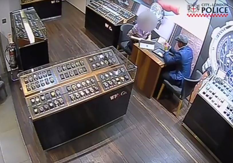  The brazen thief poses as a customer as an assistant shows him luxury timepieces for sale