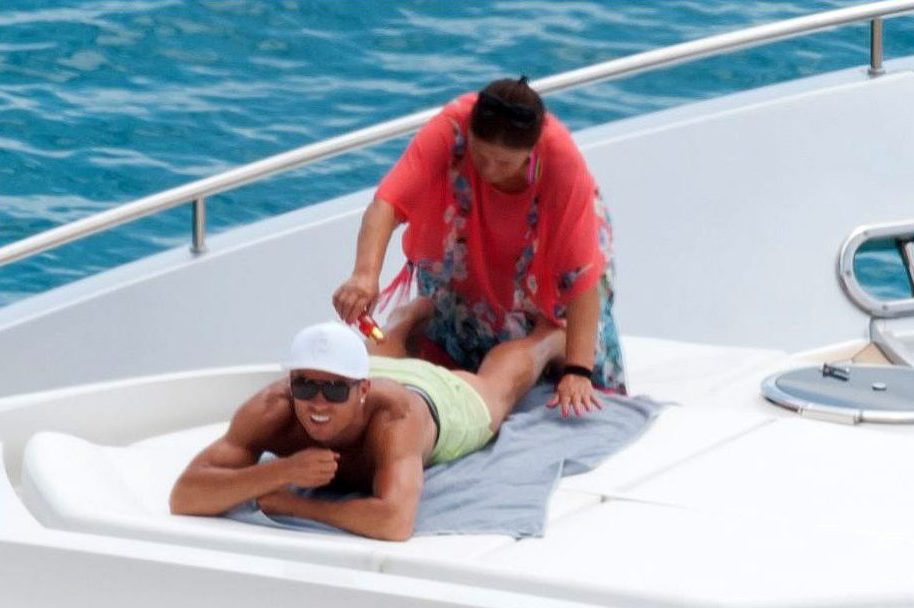  Mum's the word ... Ronaldo's mother helps her boy get oiled up before catching some rays