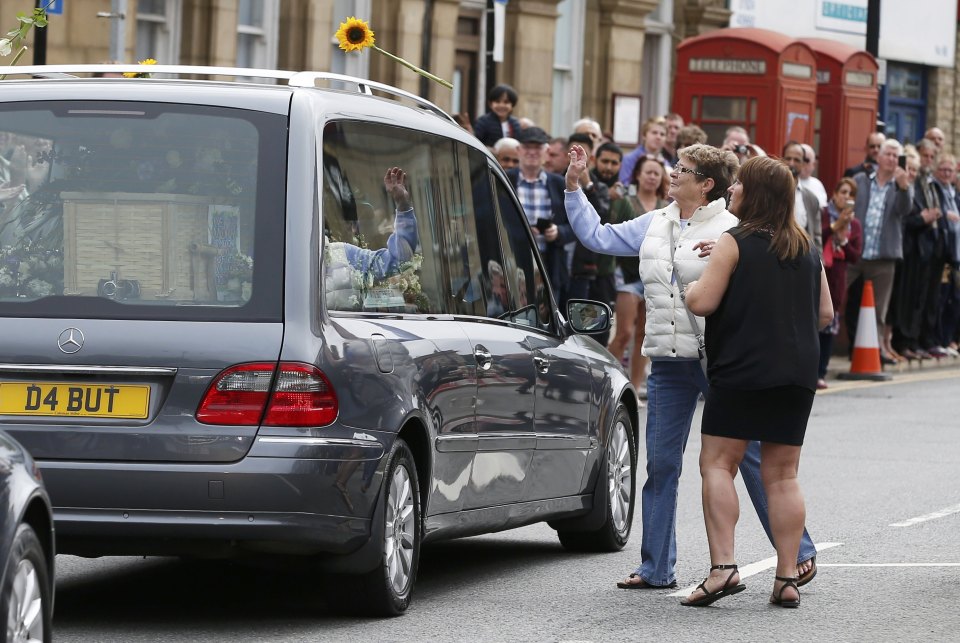 A sunflower is thrown onto the roof of the hearse carrying murdered MP Jo Cox through the town she represented