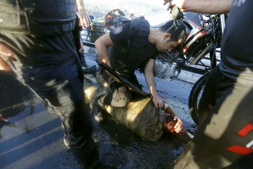 A policeman checks a soldier beaten by the mob after troops involved in the coup surrendered