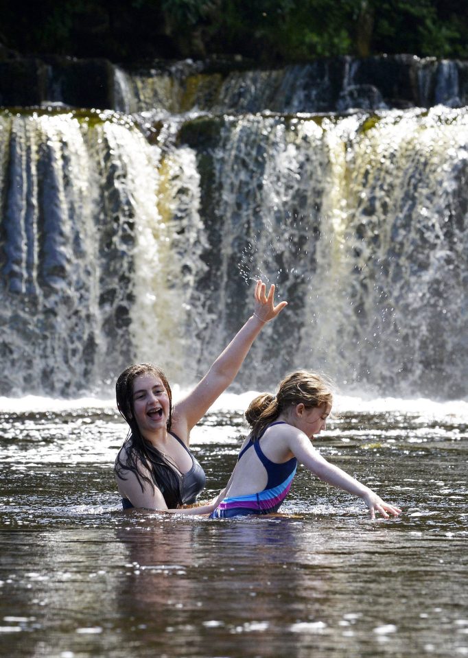  Sisters Jessica and Jasmine Robertson cool down in the River Swale at Richmond in North Yorkshire this afternoon