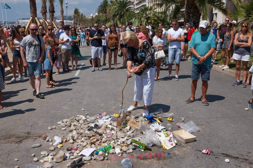  Shrine of shame . . . Woman empties bottle over rubbish marking spot where he died