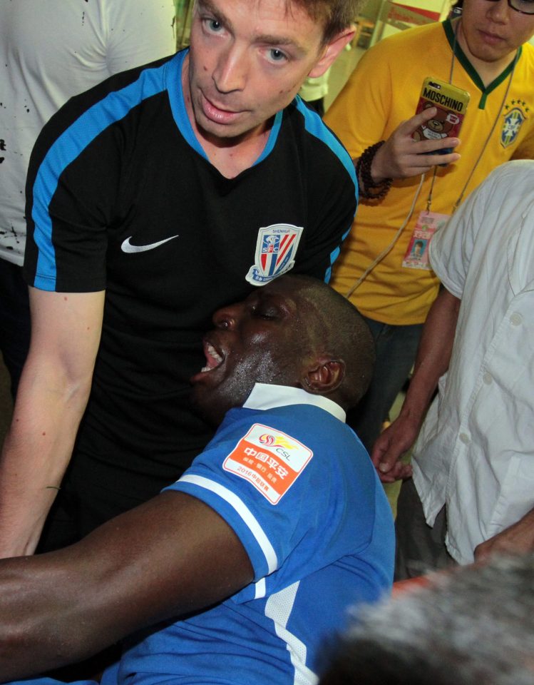 Demba Ba grimaces in pain as he is taken to hospital in China