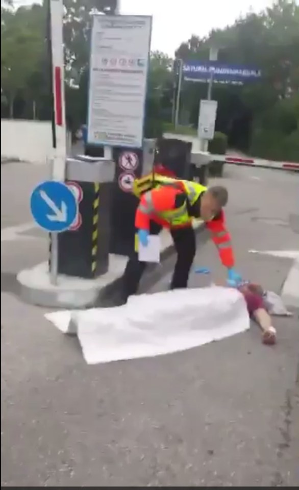 An emergency services worker covers up the body of an apparent victim