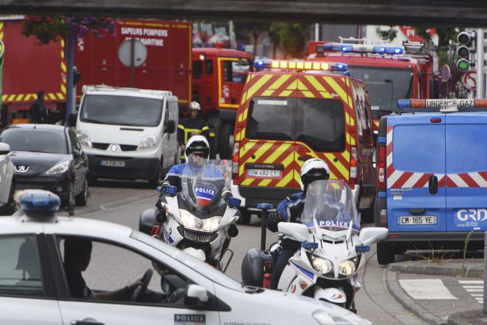 Police and rescue workers stand at the scene after two assailants had taken five people hostage in the church at Saint-Etienne-du -Rouvray near Rouen in Normandy