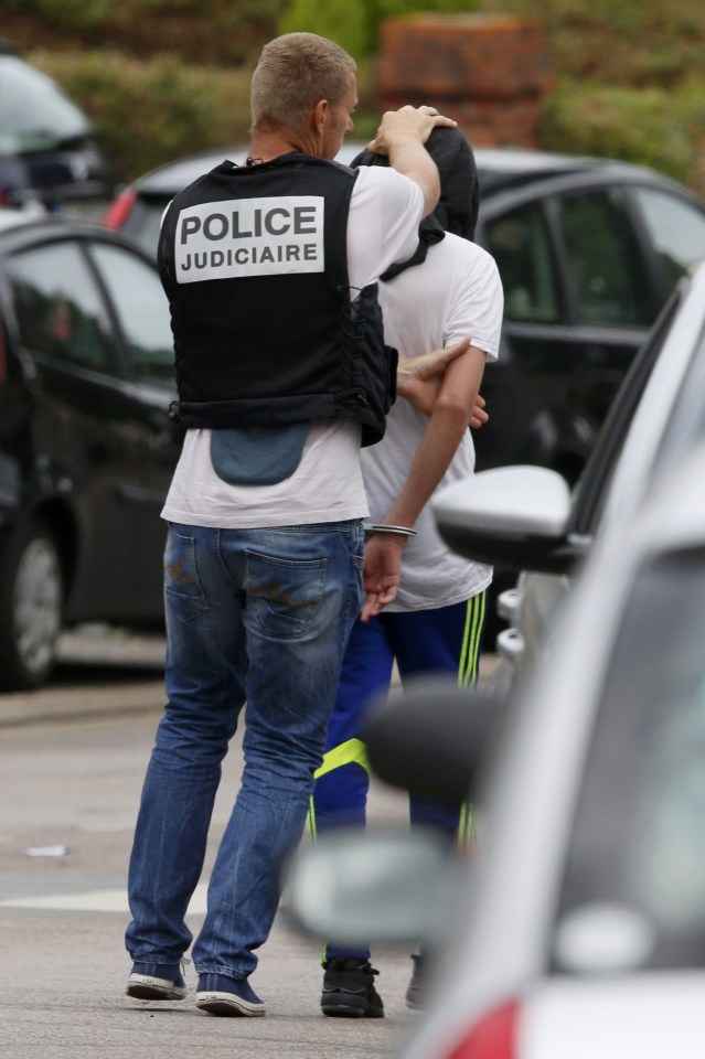  A plain-clothes police officer leads away a third suspect following the attack on the church near the city of Rouen