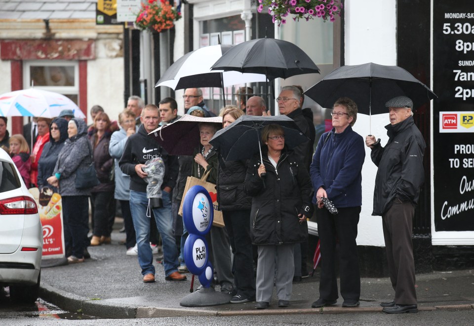 Residents stand roadside as the coffin makes its way past them