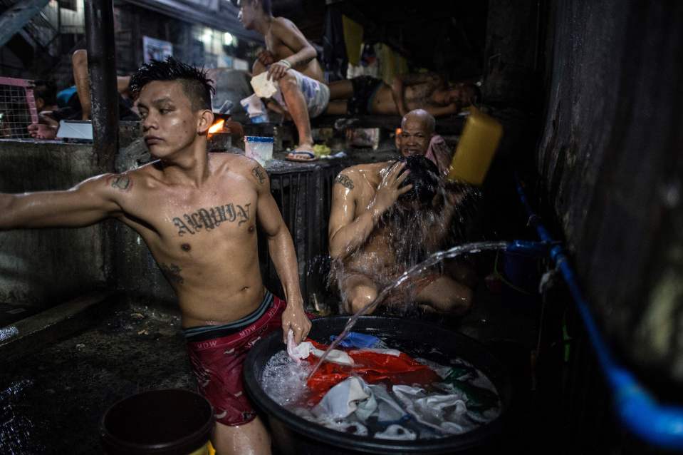  An inmate cooks his dinner as other detainees take a bath and wash their clothes