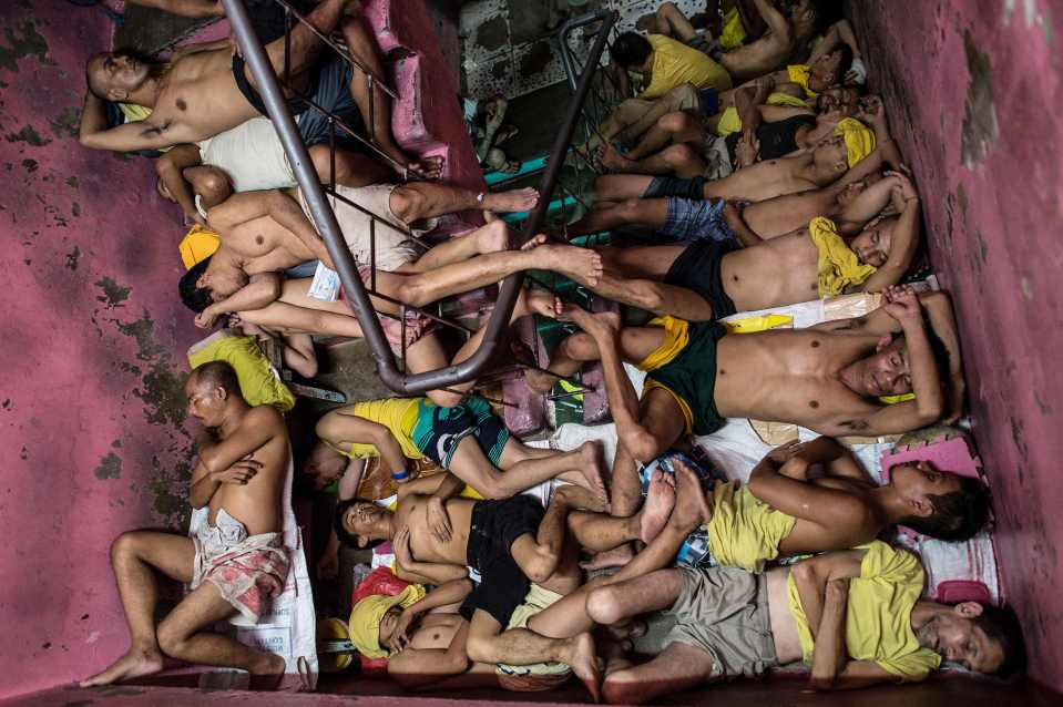  Half dressed to cope with the stifling heat they lie clustered together on the steps of the jail