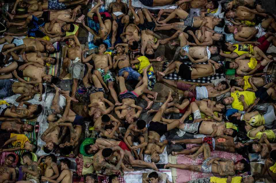  Inmates sleep on the ground of an open basketball court inside the overcrowded prison