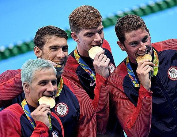 Lochte (left) was celebrating winning his sixth Olympic gold in the 4x200m freestyle relay alongside his US tem-mates, including Michael Phelps (second left)