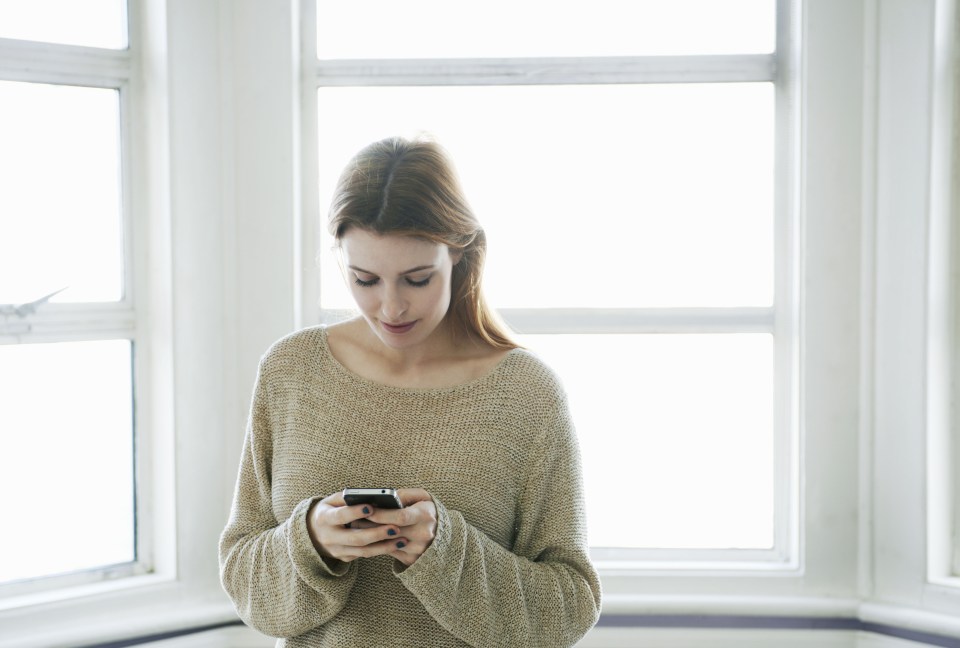 mother holding crying son and talking on cell phone