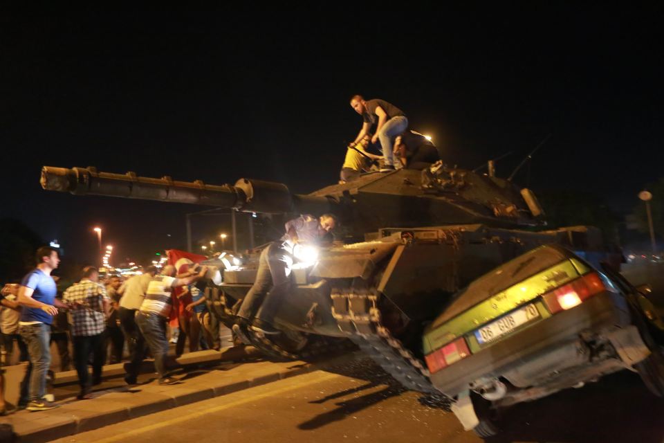 A tank moves into position, crushing a car as people attempt to stop it in Ankara on 16 July