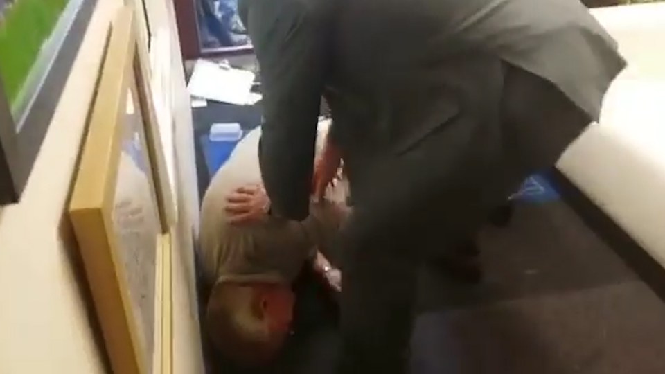 After getting back up, the man in blue appears to shove another man who then falls to the floor