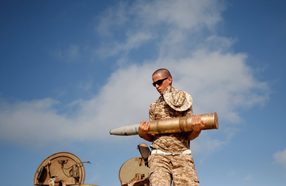 A fighter of Libyan forces allied with the U.N.-backed government carries a 122 mm tank shell on top of a Soviet made T-55 in Sirte