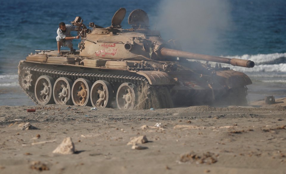 Fighters of Libyan forces allied with the U.N.-backed government move from a beach after they fired shells with Soviet made T-55 tank at Islamic State fighters in Sirte