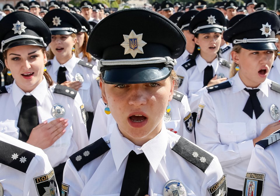 Police officers sing the national anthem during a ceremony to mark the 1st anniversary of a reformed police service