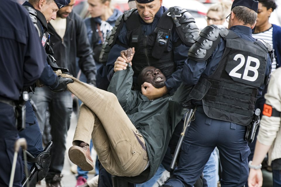  A migrant struggles as he is hauled away from the camp in north Paris