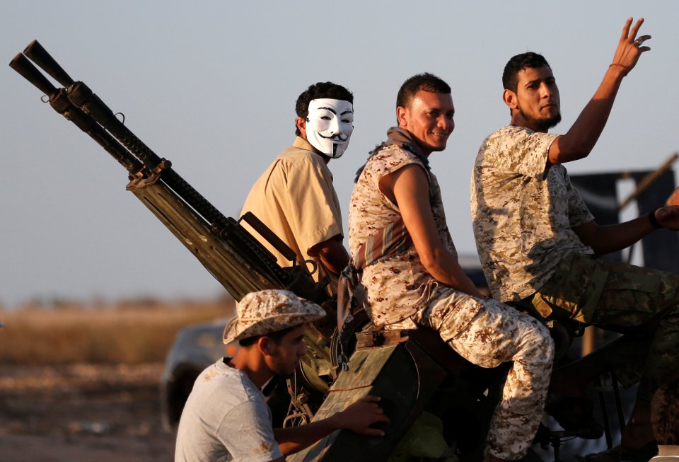 A fighter of Libyan forces allied with the U.N.-backed government wears a mask as he waits with other fighters for a rocket to be fired at Islamic State fighters in Sirte