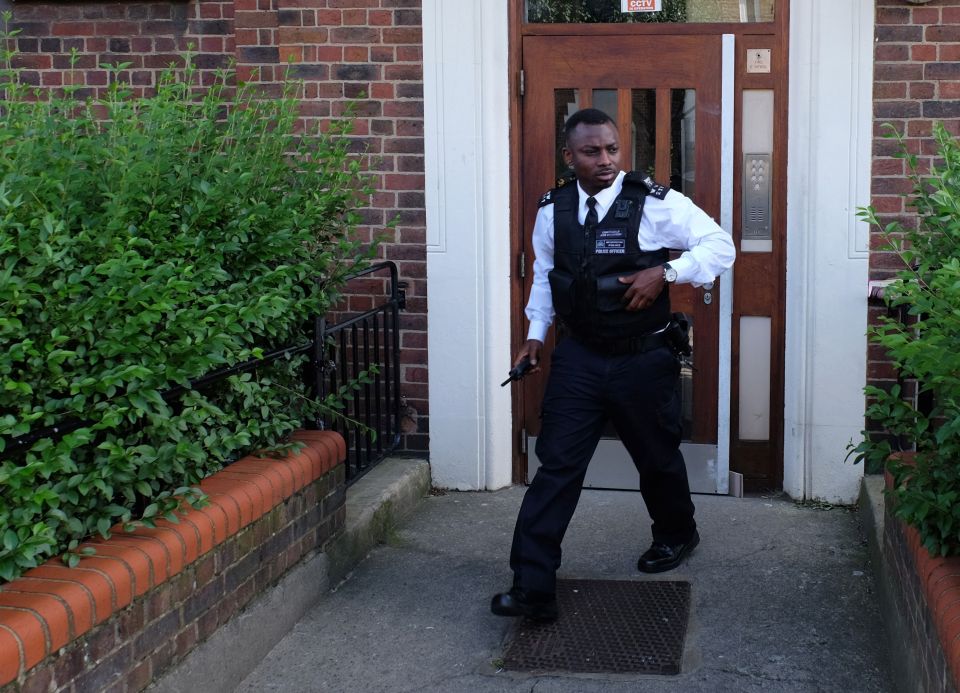 A police officer exits Bulham's home, which is being searched by cops today