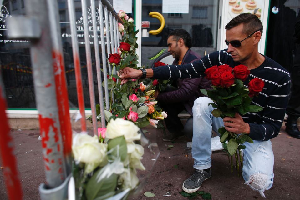  Men lay flowers in front of barrier set up outside the bar