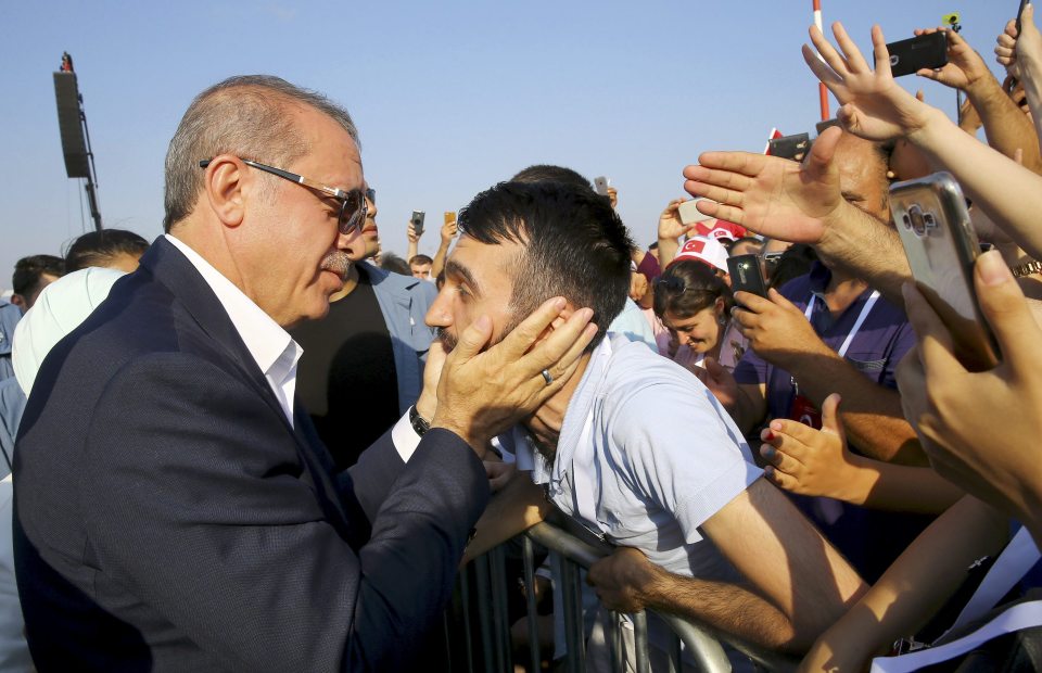 Turkey's President Erdogan holds a head of man as he attends the Democracy and Martyrs Rally in Istanbul