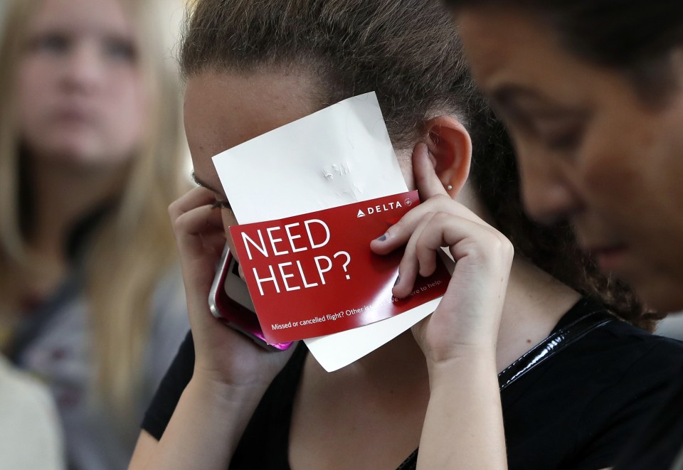  Konstance Woods talks on her cell phone with an agent as she stands in line at the Delta ticketing counter at Washington's Ronald Reagan Washington National Airport, as her family tries to get to Raleigh, N.C., after their Delta flight was delayed