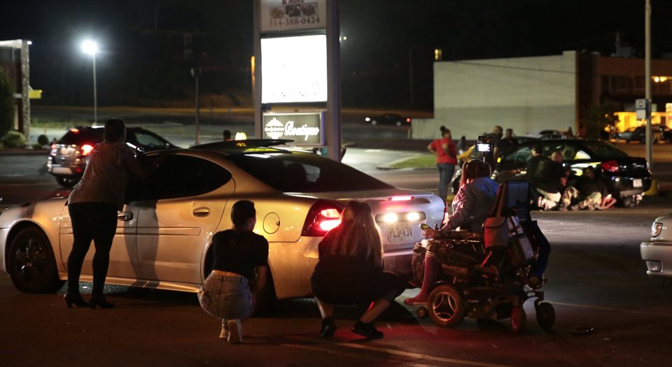 Protesters hide behind cars after shots were fired during the demonstration