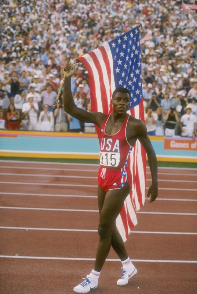  Carl Lewis proudly carries the American flag after his 100m gold medal