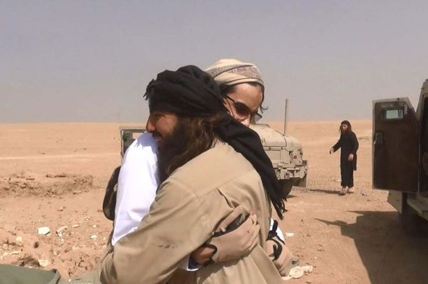 Al-Baljiki, seen here dressed in white, embraces a fellow jihadists as he prepares to carry out a suicide mission