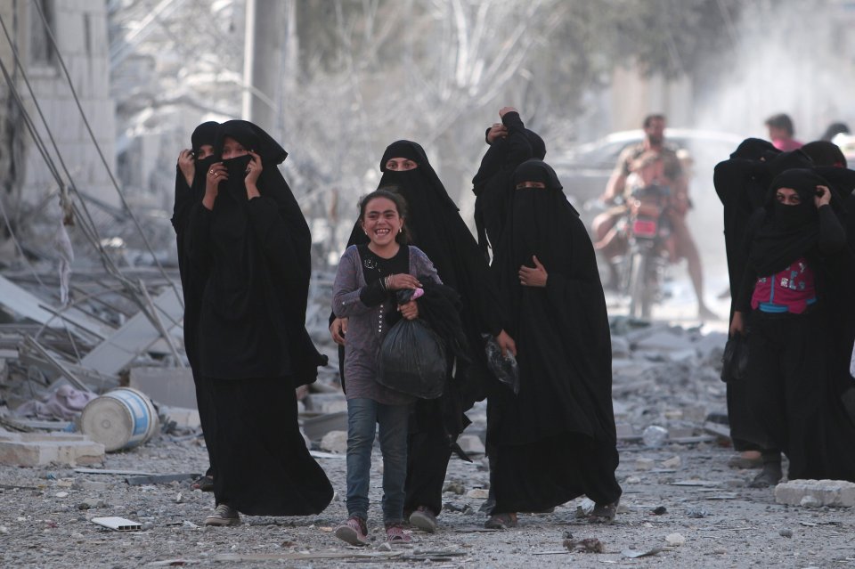  A girl smiles as she walks through the war torn streets of Manbij