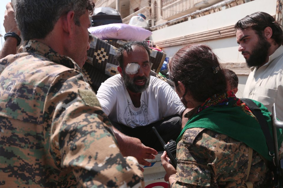  Syria Democratic Forces (SDF) fighters talk with an injured man