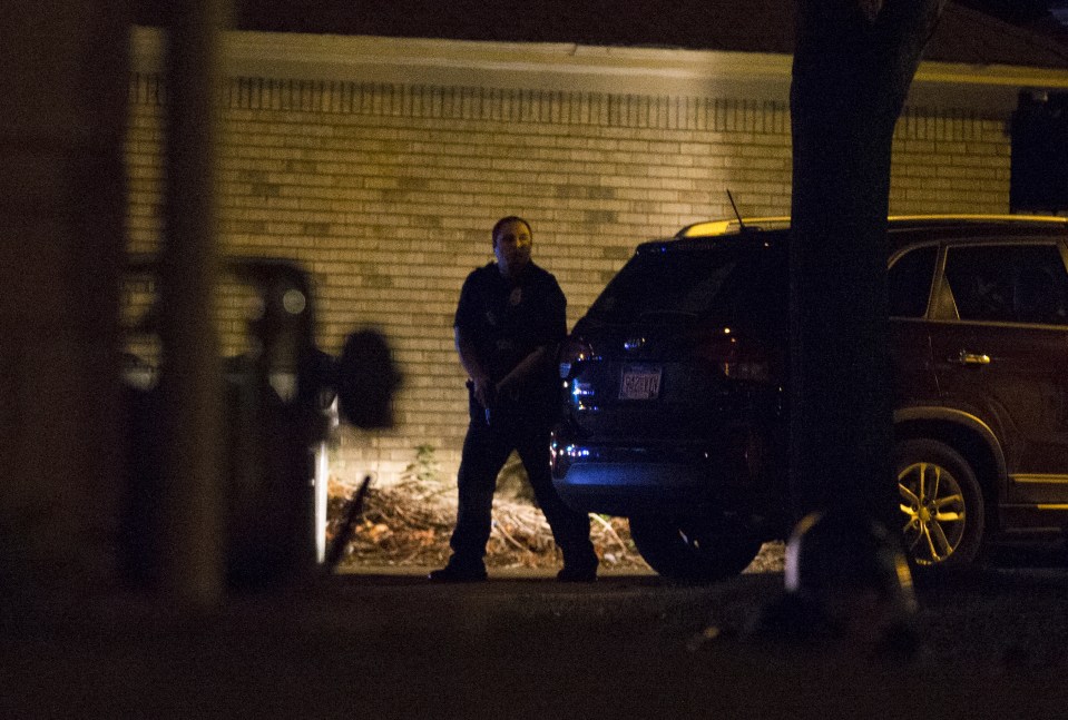  A police officer hides behind a car as a crowd as the crowd converges