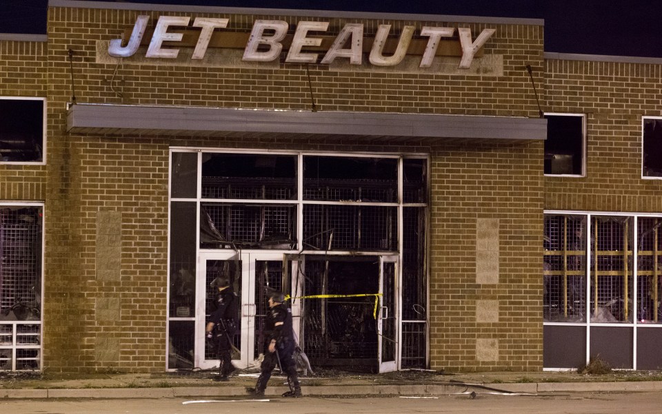  Officers walk past a store in riot gear