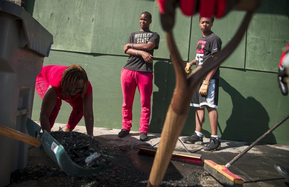  Community volunteers clean up the damage caused to the area after the riots