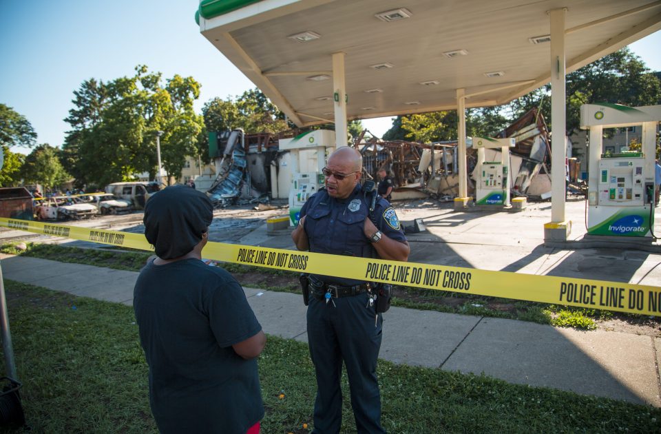  A policeman consults a resident at the riot scene