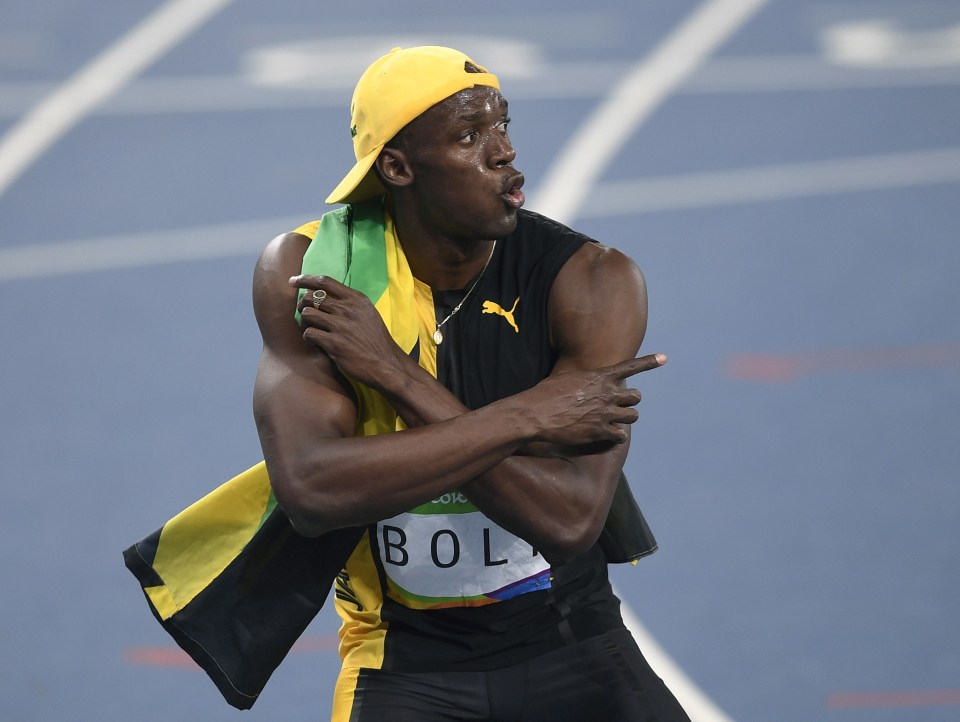  Usain Bolt goofs around in a baseball cap and draped in the Jamaica flag after his victory