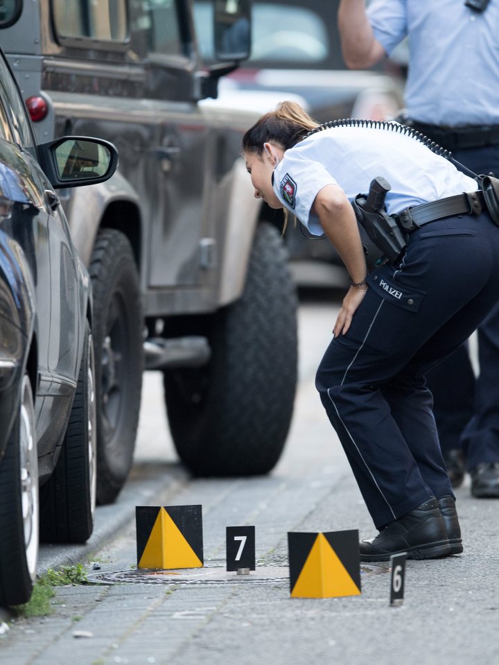  Police inspect cars at the scene where a man was stabbed and shot at in Cologne's town centre