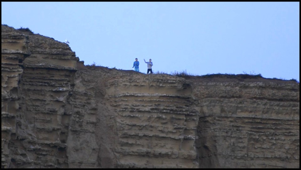  Video footage shows two boys on top of the cliff throwing rocks and stones at the beach