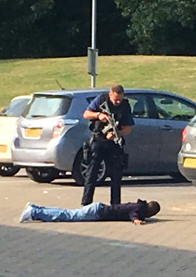  An armed police officer stands over one of the men