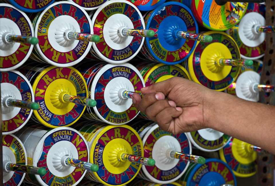 An Indian kite-maker removes a reel of kite string to be used. The use of glass-coated string has been banned