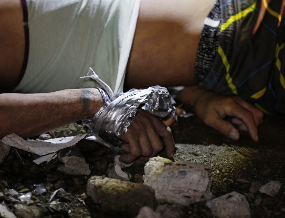  Suspected drug dealer shot dead by an unidentified gunman lies on the ground as investigators survey the scene