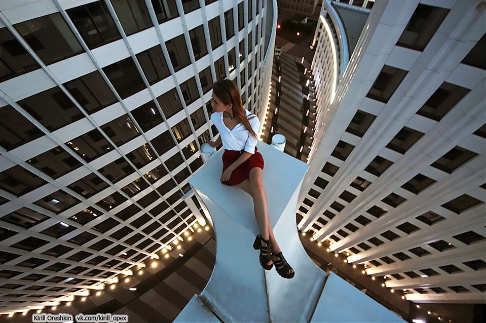 The young woman dangles her legs precariously over the edge