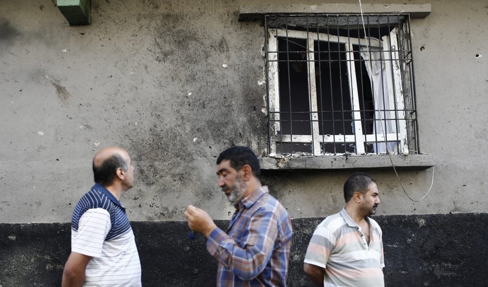  People stand below a shattered window that was damaged during the attack