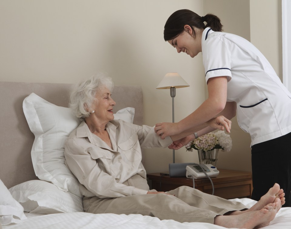 Nurse rolling up elderly woman's sleeve