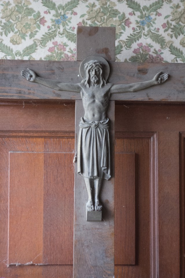 A statue of Jesus hangs on the wooden wall of the creepy old dentist's clinic