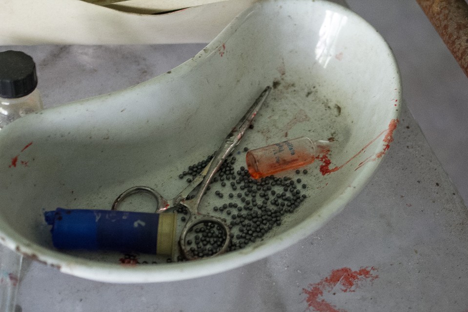 A set of rusty utensils and pills lie discarded in a bowl